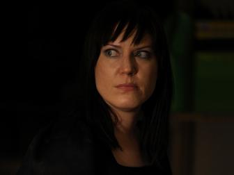 Amy shoots a concerned glance across a dark room during her walk.
