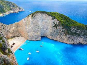 Yachts & pleasure boats moored in the turquoise waters just off Shipwreck Beach of Zakynthos. To the locals it's known as Navagio Beach. Stranded on the sand is the wreck of the Panagiotis (originally built in Scotland in 1937, and called the Saint Bedan), wrecked in 1980 and possibly engaged in nefarious, smuggler-type activities.