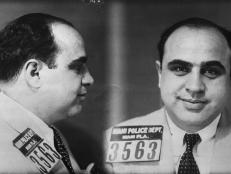 A black and white mug shot of Al Capone wearing a suit and tie.