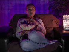 Woman relaxing at home with popcorn in front of the TV.